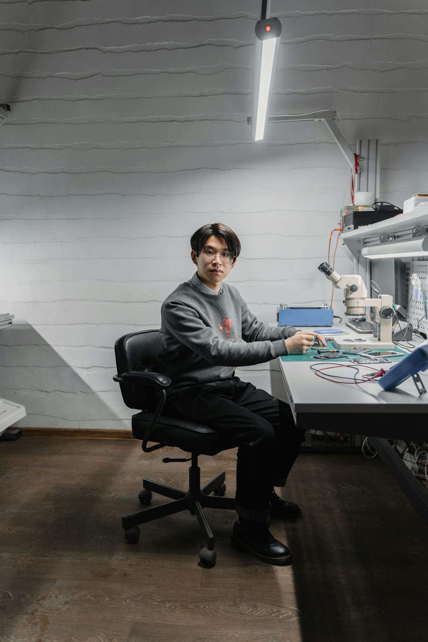 A skilled technician at a workbench in a modern electronics lab repairing a device.