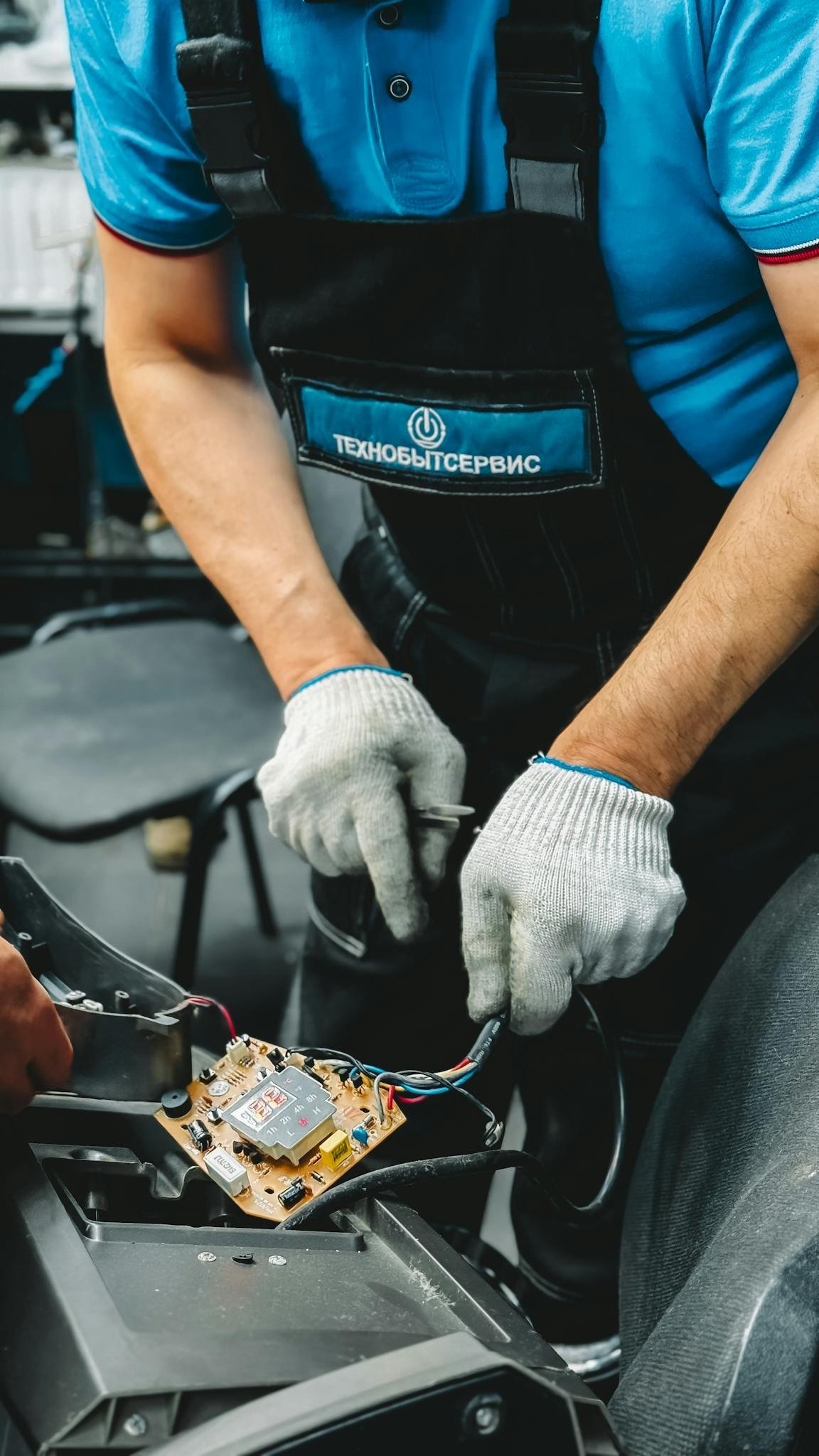 Close-up of technician in gloves fixing electronic device, showcasing repair skills.